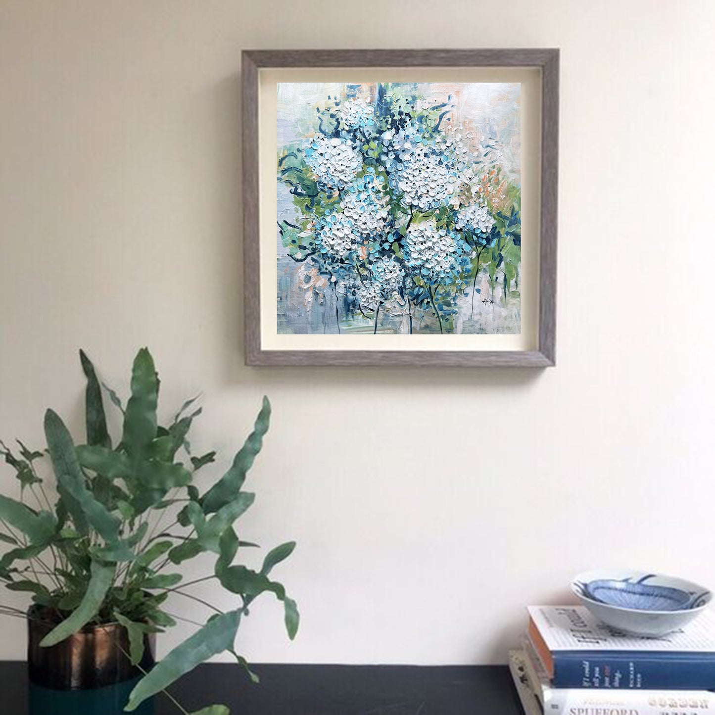 a painting hanging on a wall next to a potted plant